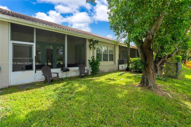 rear view of house featuring a sunroom and a lawn