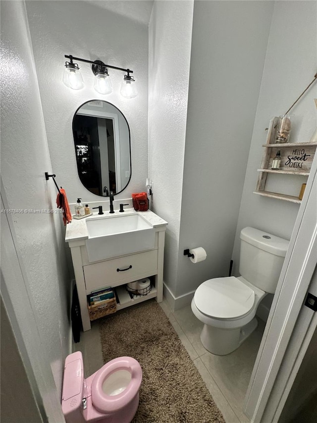 bathroom with toilet, vanity, and tile patterned floors