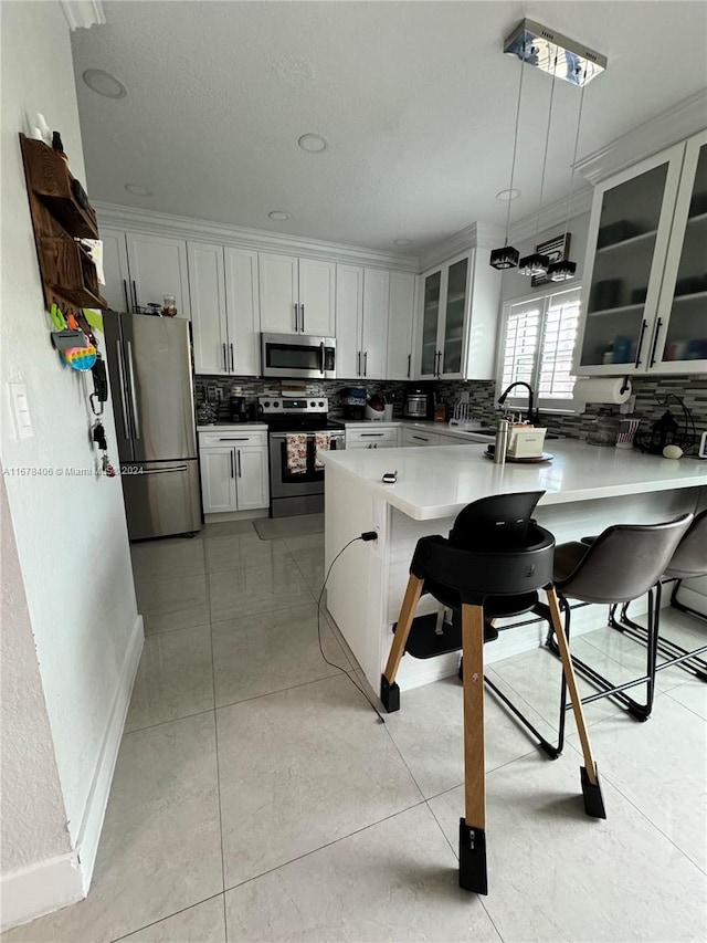 kitchen with decorative backsplash, appliances with stainless steel finishes, a kitchen bar, and decorative light fixtures