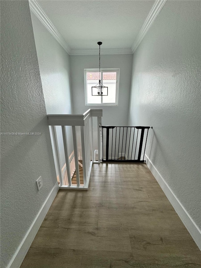 stairway featuring crown molding, an inviting chandelier, and hardwood / wood-style floors