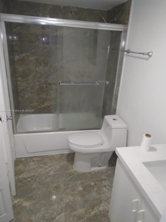 bathroom with toilet, vanity, and enclosed tub / shower combo