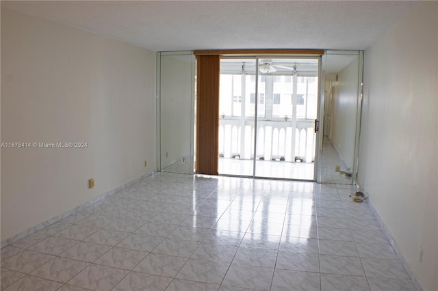 tiled spare room with ceiling fan, a textured ceiling, and floor to ceiling windows