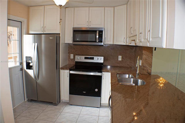 kitchen with white cabinetry, dark stone countertops, stainless steel appliances, and sink