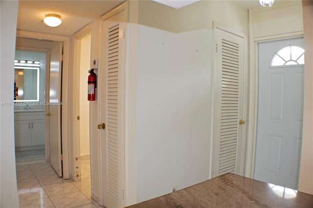 hall with sink, light tile patterned flooring, and a textured ceiling