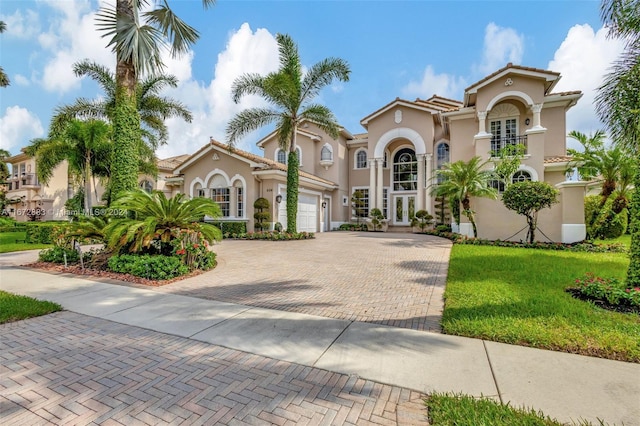 mediterranean / spanish-style home with a front lawn, a garage, and french doors