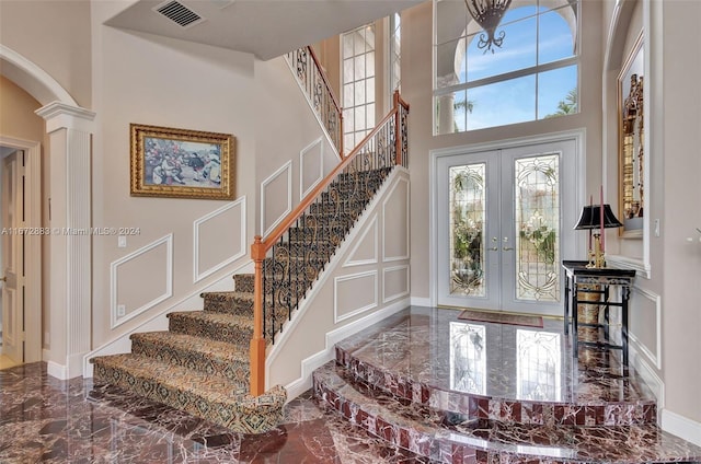 entrance foyer featuring ornate columns, french doors, and a towering ceiling