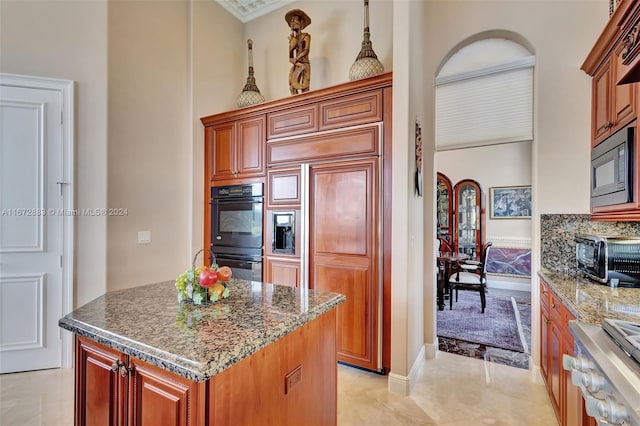 kitchen with built in appliances, stone countertops, a kitchen island, and ornamental molding