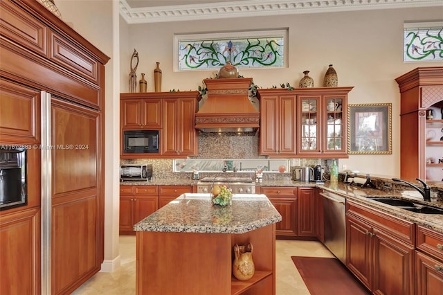 kitchen with tasteful backsplash, light stone counters, sink, built in appliances, and a kitchen island