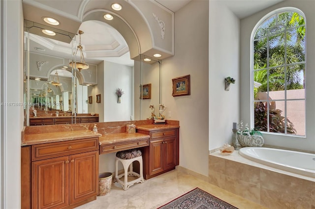 bathroom with a tray ceiling, tiled bath, vanity, and ornamental molding