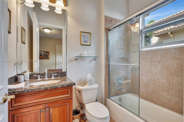 full bathroom featuring vanity, bath / shower combo with glass door, and toilet