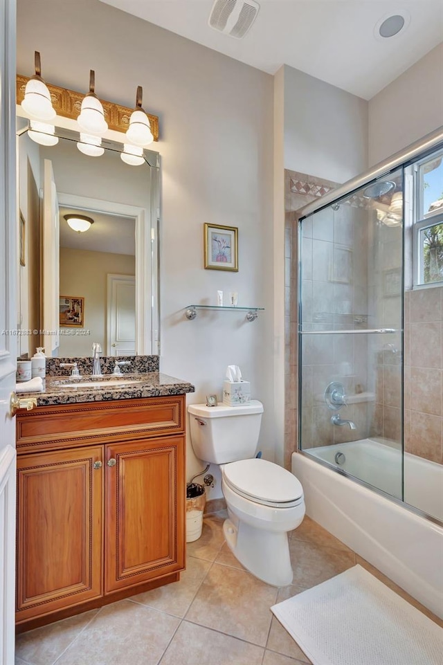 full bathroom with tile patterned floors, vanity, bath / shower combo with glass door, and toilet