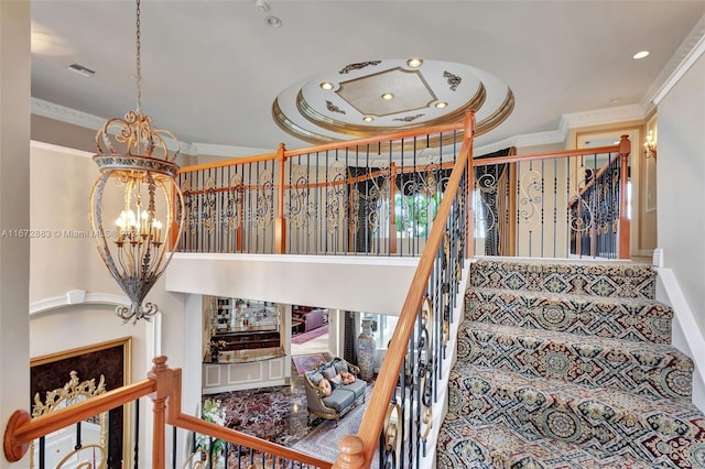 stairs featuring a notable chandelier, ornamental molding, and a fireplace