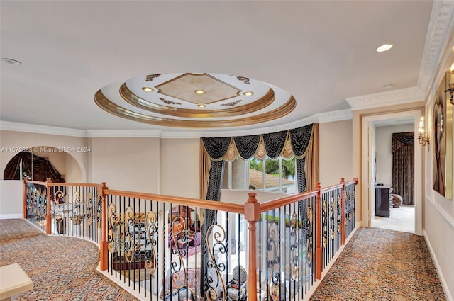 hall with a tray ceiling and ornamental molding