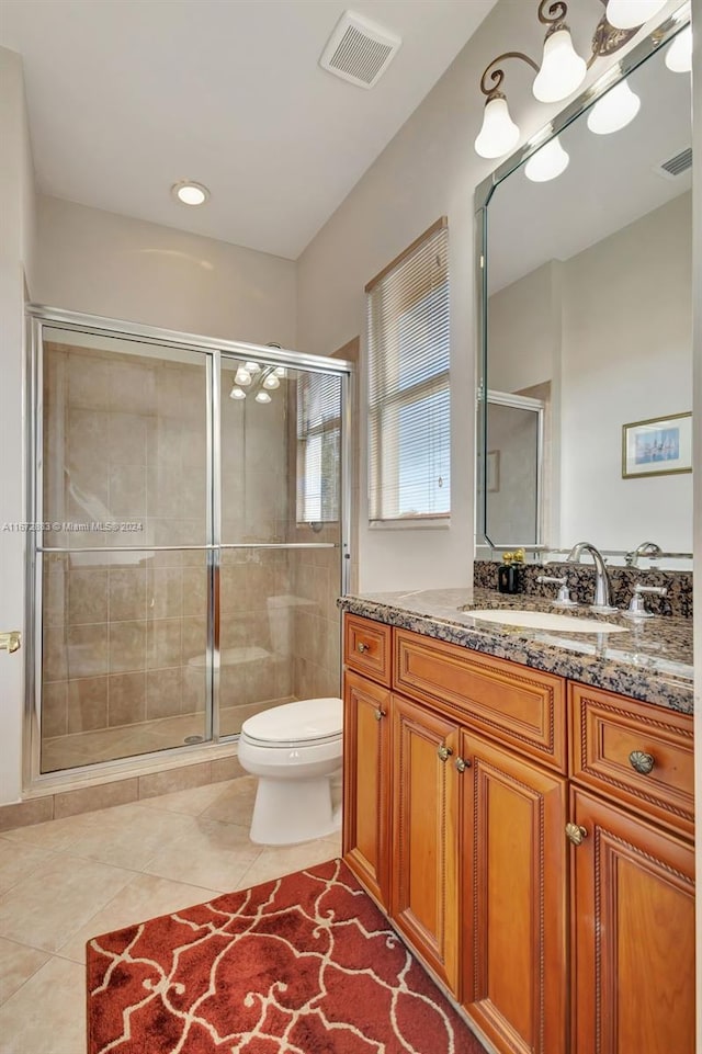 bathroom featuring tile patterned flooring, vanity, toilet, and a shower with door