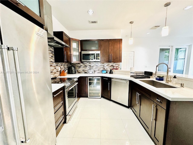 kitchen with sink, hanging light fixtures, light tile patterned floors, appliances with stainless steel finishes, and beverage cooler