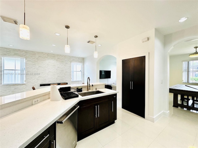 kitchen with sink, light tile patterned flooring, hanging light fixtures, and stainless steel dishwasher