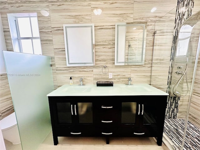 bathroom with a shower with door, vanity, tile walls, and toilet