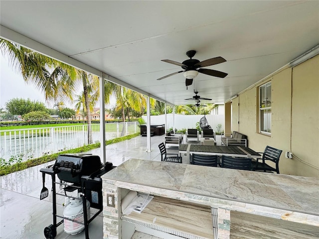 view of patio / terrace with outdoor lounge area, ceiling fan, an outdoor bar, grilling area, and a water view