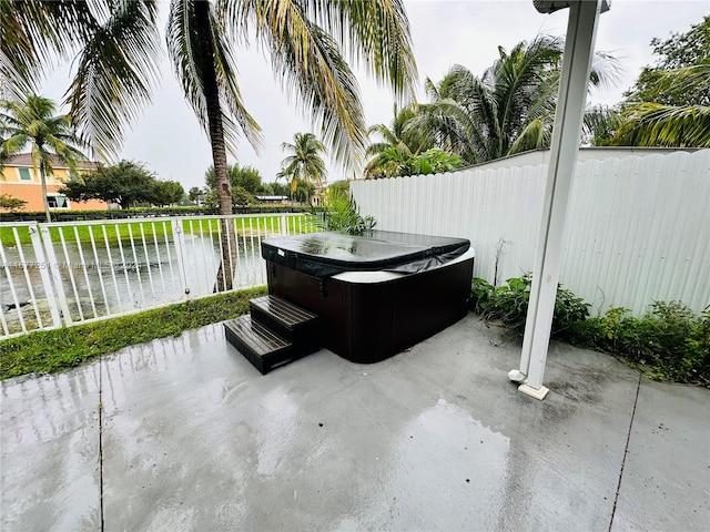 view of patio featuring a water view and a hot tub