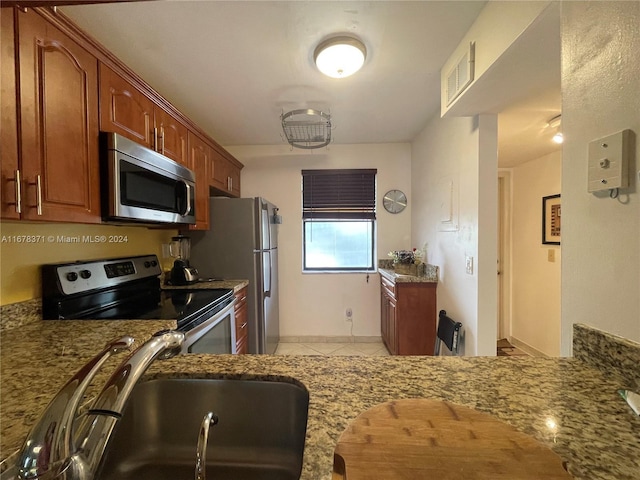 kitchen with visible vents, appliances with stainless steel finishes, a sink, light stone counters, and light tile patterned flooring
