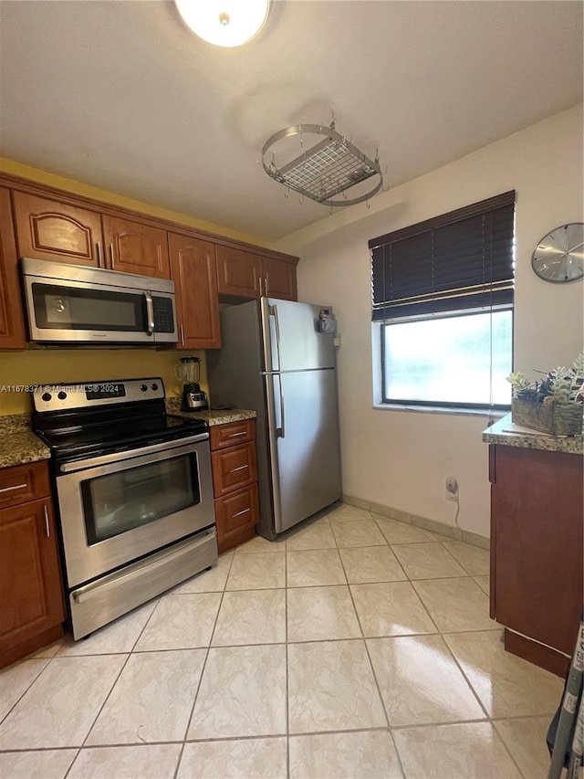 kitchen featuring light stone counters, stainless steel appliances, and light tile patterned flooring