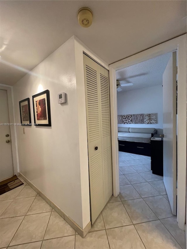 hallway featuring a textured ceiling and light tile patterned flooring