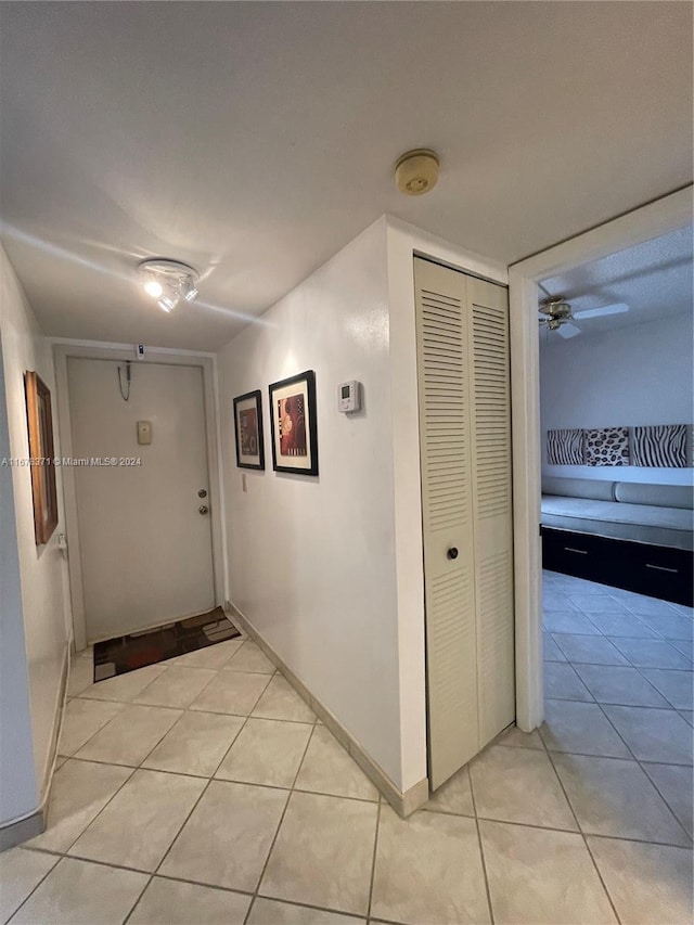 hall featuring baseboards and light tile patterned floors