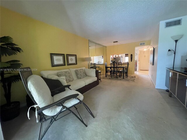 living room featuring a notable chandelier, a textured ceiling, visible vents, and light carpet
