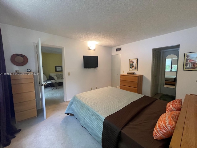 bedroom featuring light carpet, a textured ceiling, and visible vents