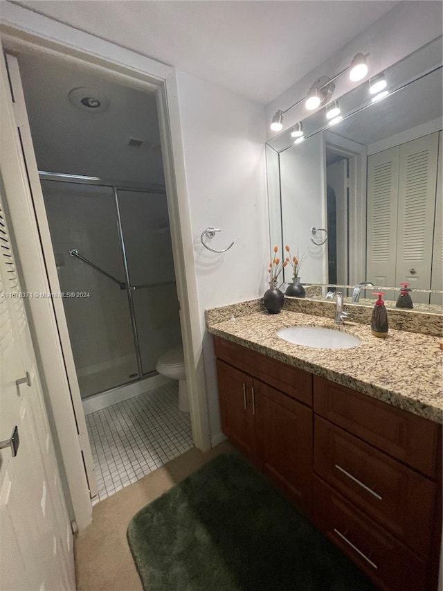 bathroom with vanity, an enclosed shower, toilet, and tile patterned flooring