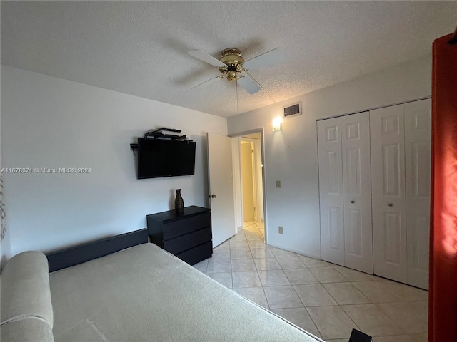 tiled bedroom featuring a closet, a textured ceiling, and ceiling fan