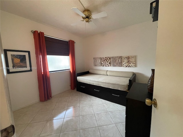 bedroom featuring ceiling fan, a textured ceiling, and light tile patterned floors