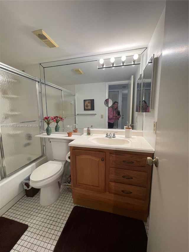 bathroom featuring visible vents, tile patterned flooring, vanity, toilet, and combined bath / shower with glass door