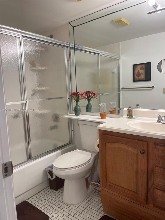 full bathroom with tile patterned flooring, combined bath / shower with glass door, toilet, and vanity