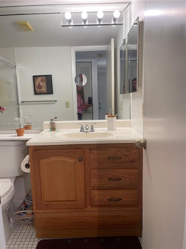 bathroom featuring tile patterned flooring, vanity, toilet, an enclosed shower, and visible vents