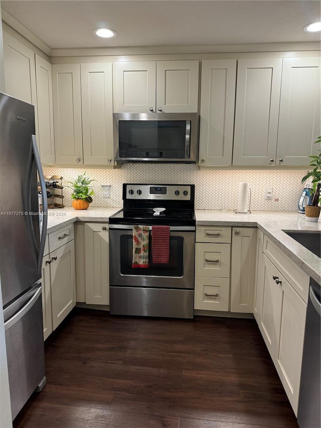 kitchen featuring dark wood-type flooring, tasteful backsplash, appliances with stainless steel finishes, and white cabinets