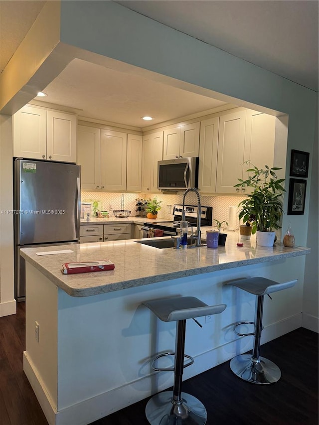 421 SE 10th St Unit A205, Dania Beach, FL 33004 - kitchen with stainless steel appliances, dark wood-style floors, white cabinets, a peninsula, and recessed lighting
