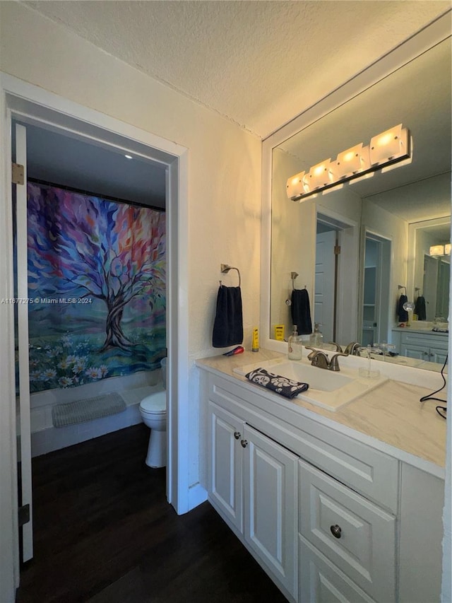 bathroom with toilet, wood-type flooring, vanity, a textured ceiling, and walk in shower