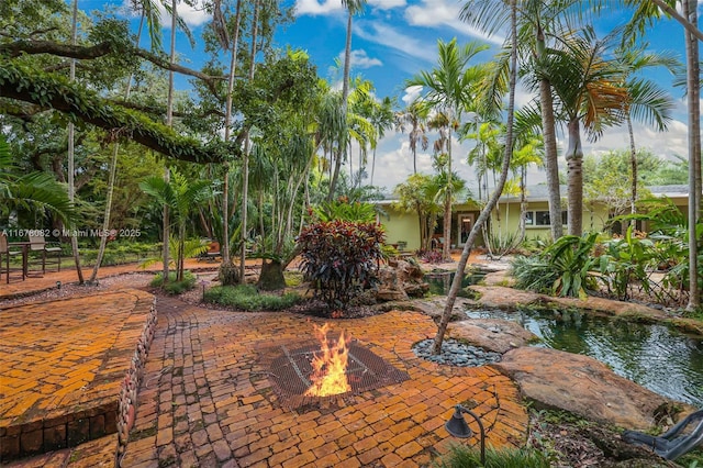 view of property's community featuring a patio and an outdoor fire pit