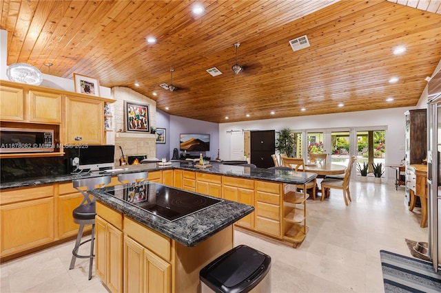 kitchen with black electric stovetop, a kitchen breakfast bar, kitchen peninsula, and a kitchen island