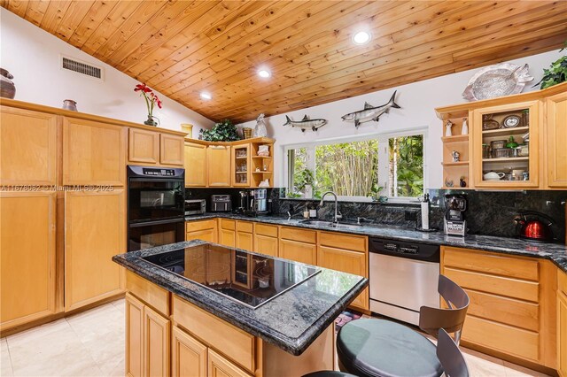 kitchen with dark stone countertops, sink, black appliances, and a kitchen island