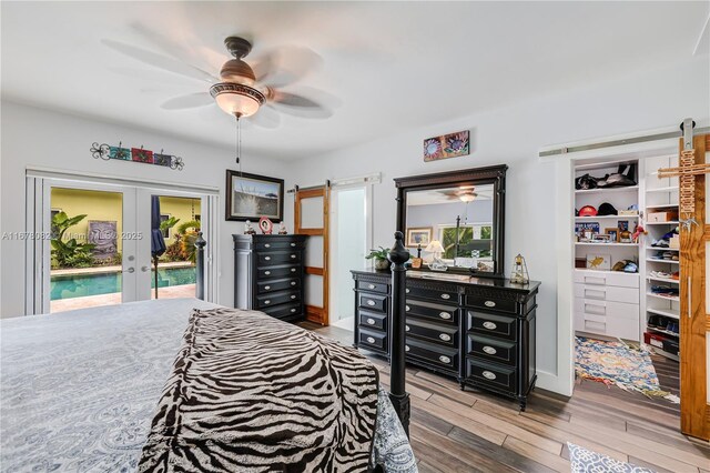 bedroom with ceiling fan, access to exterior, hardwood / wood-style floors, french doors, and a barn door