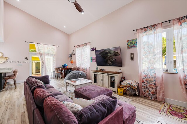 living room featuring ceiling fan, high vaulted ceiling, and light wood-type flooring