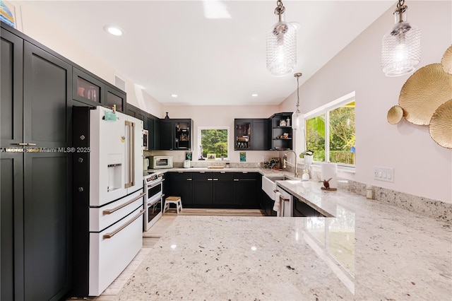 kitchen featuring range with two ovens, light stone countertops, white refrigerator with ice dispenser, and hanging light fixtures