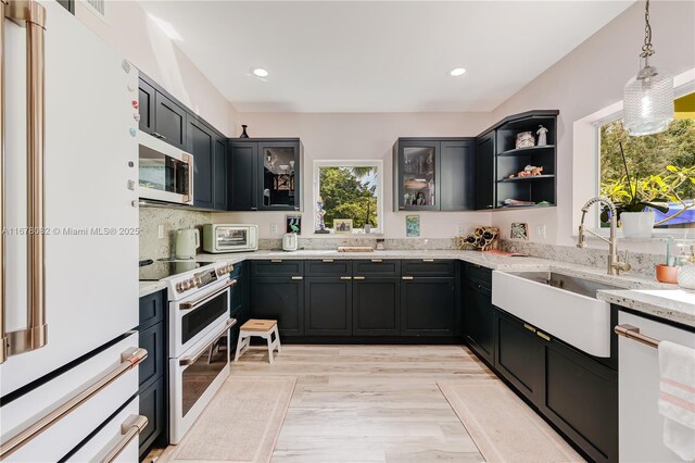 kitchen with light stone countertops, sink, pendant lighting, and white dishwasher