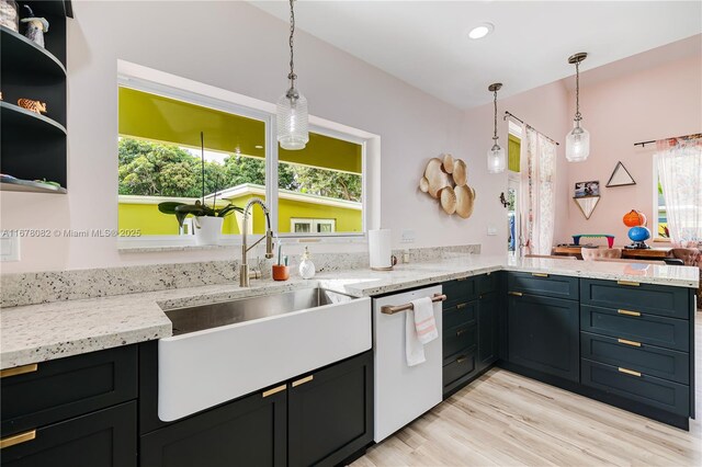 kitchen with pendant lighting, sink, light stone countertops, and dishwasher