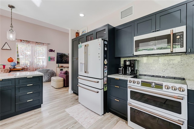 kitchen with light stone counters, hanging light fixtures, light hardwood / wood-style flooring, white appliances, and decorative backsplash