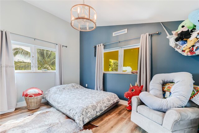 bedroom with a chandelier, vaulted ceiling, and light hardwood / wood-style flooring