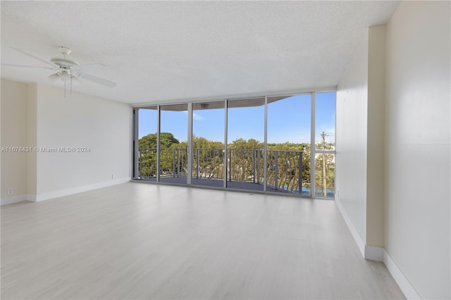 spare room with ceiling fan, a textured ceiling, light hardwood / wood-style flooring, and floor to ceiling windows