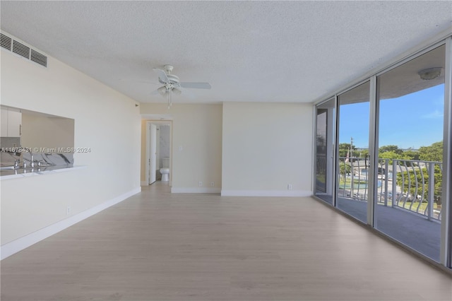 unfurnished room featuring floor to ceiling windows, a textured ceiling, light hardwood / wood-style floors, and ceiling fan